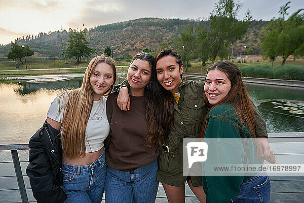A group of beautiful young women posing near a lake in a park on a sum