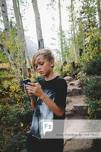 Tween Boy Checks Phone While on a Hike in Colorado.