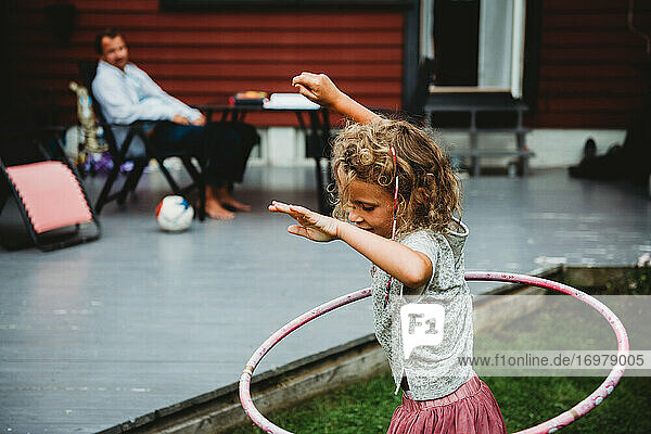 Seitenansicht von niedlichen Mädchen spielen mit Hula-Hoop-Reifen im Sommer im Hinterhof