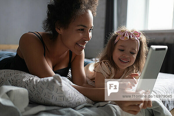 Gemischtrassige andere und Tochter spielen zu Hause auf dem Tablet