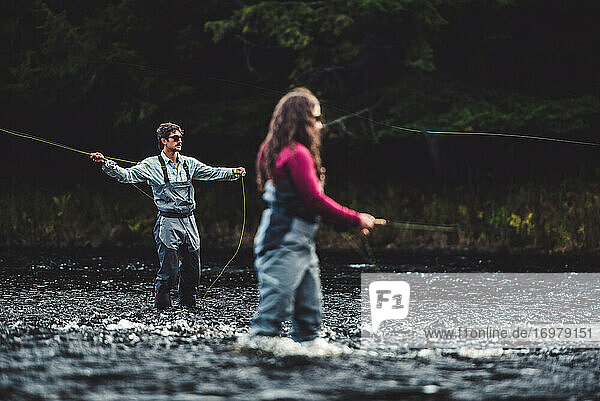 Ein Mann und eine Frau angeln in einem Fluss mit dunklem Hintergrund