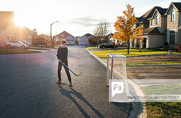 Ein Jugendlicher spielt in einer Wohnstraße Streethockey mit einem Ripstick.