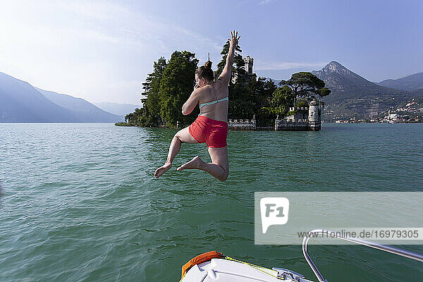 Ein Mädchen springt von einem Boot in einen See in Italien.