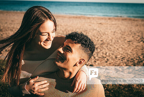 Junges Paar in der Liebe umarmt und lächelnd am Strand