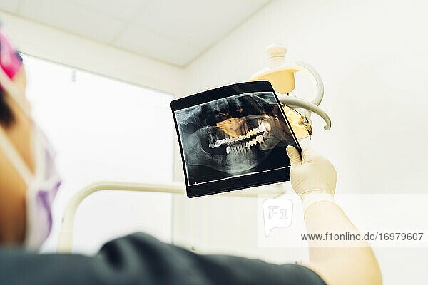 Zahnarzt  der vor der Operation ein Röntgenbild betrachtet