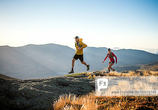 Man and woman trail running in mountains at sunrise
