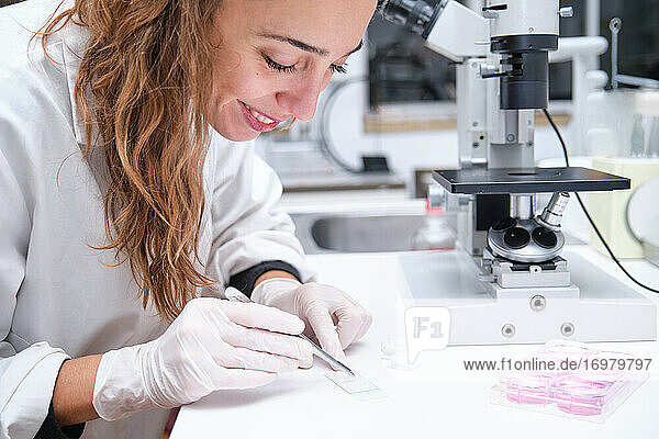 Junge Wissenschaftlerin bereitet Proben vor  um sie durch ein Mikroskop in einem Labor zu betrachten. Laborforschungskonzept.