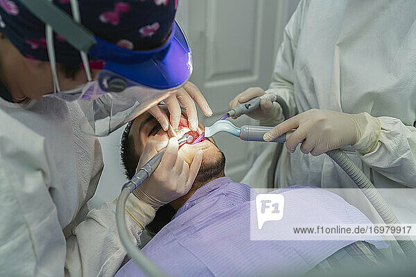 Team von Zahnärzten beim Entfernen eines Zahns bei einem Patienten