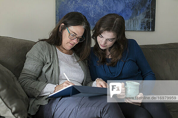 Eine Mutter und ihre Tochter arbeiten gemeinsam an einem Tablet