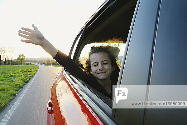 Das Mädchen im Auto streckte die Hand in den Wind. Reisen.