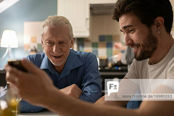 Young man showing funny photos to father