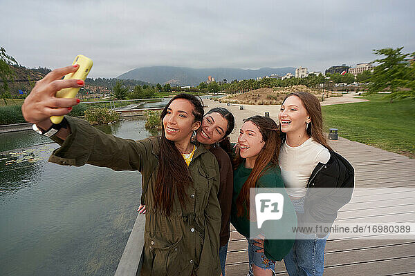 A group of beautiful women take a selfie in the city center park by a
