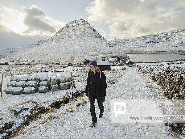 Woman walking up snowy path near Vidareidi in the Faroe Islands