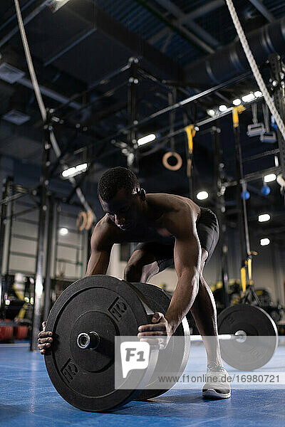 Schwarzer Sportler bei der Vorbereitung einer Kreuzhebeübung im Fitnessstudio
