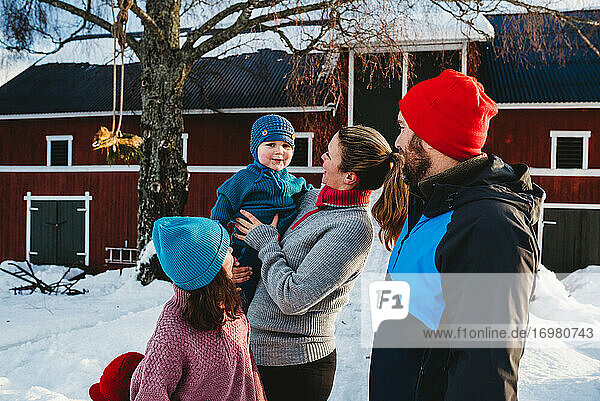 Glückliche Familie versammelt durch rote skandinavische Bar im kalten Winter mit Schnee
