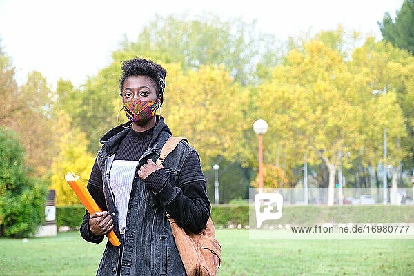 Afrikanische Studentin an der Universität  die draußen auf dem Campus eine Gesichtsmaske trägt. Die neue Normalität im College.