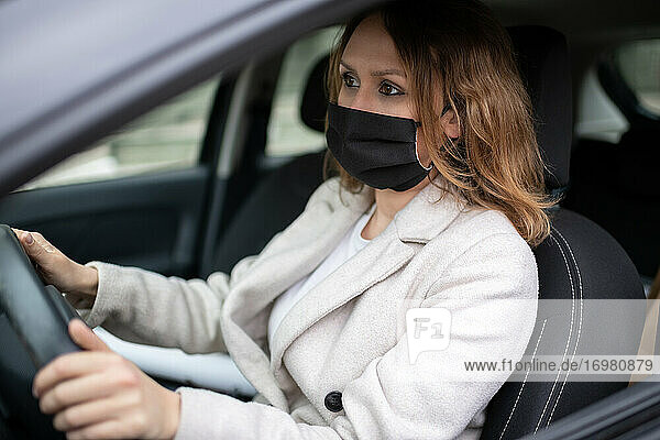 Frau mit Schutzmaske fährt Auto