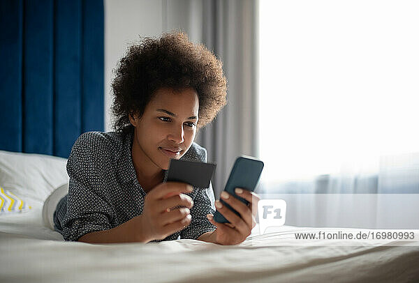 Schwarze Frau  die ihre Kreditkartendaten in ihr Smartphone eingibt