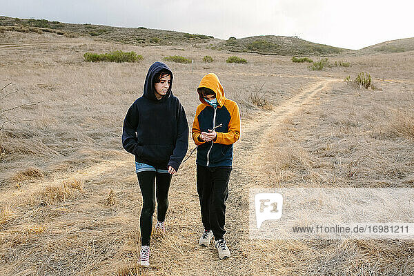 Sister And Brother Walk Along A Hiking Trail In Southern California