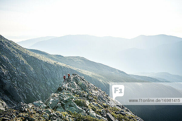 Mann und Frau wandern am Morgen auf einem Bergrücken in den Bergen