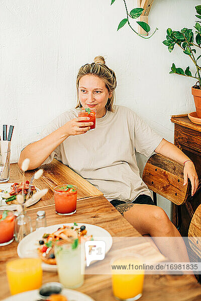 Junge Frau trinkt kalte Limonade  während sie in einem Cafe sitzt