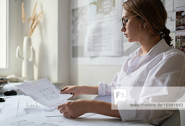 Aufmerksame Geschäftsfrau liest Entwurf im Büro
