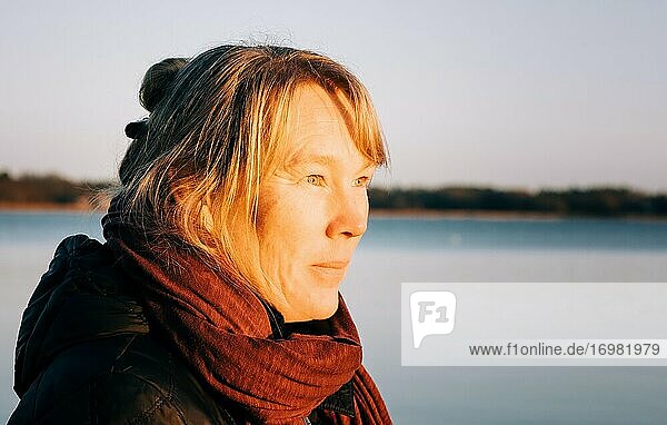 Nahaufnahme einer schwedischen Dame mit Blick auf das Meer bei Sonnenuntergang
