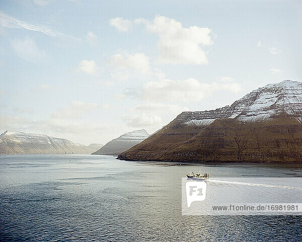Boat going between two mountains in the Faroe Islands