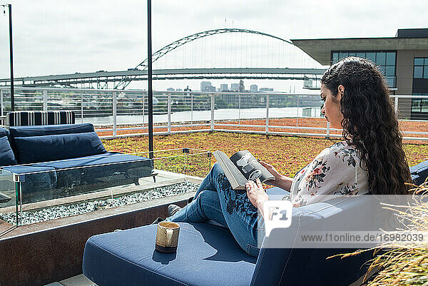Frau liest ein Buch auf dem Dach draußen mit Brücke und Stadt