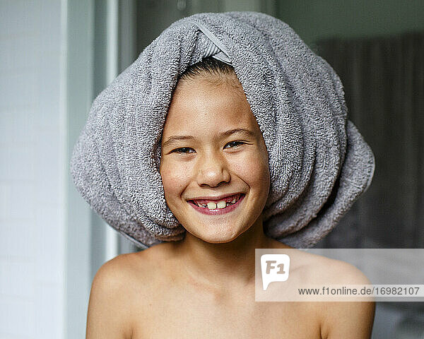 Porträt eines fröhlichen Jungen mit einem breiten Grinsen und einem Badetuch auf dem Kopf