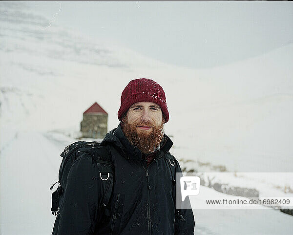 Porträt eines lächelnden  bärtigen Mannes im Schnee  der in die Kamera schaut  auf den Färöer Inseln