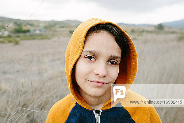 Portrait Of A Boy Wearing An Orange Hoodie Outside In Nature