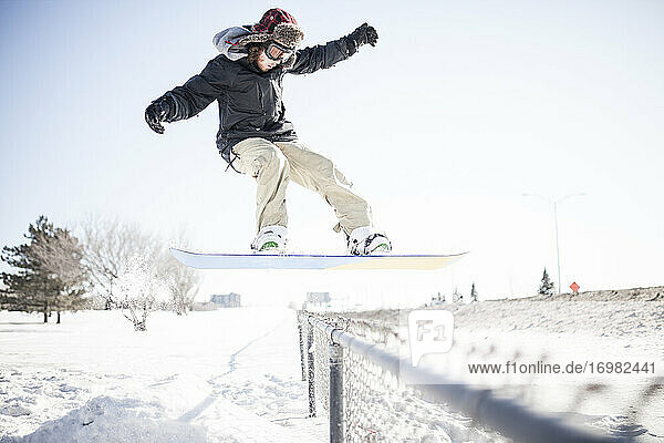 Junger Snowboarder führt einen Stunt in der Luft aus