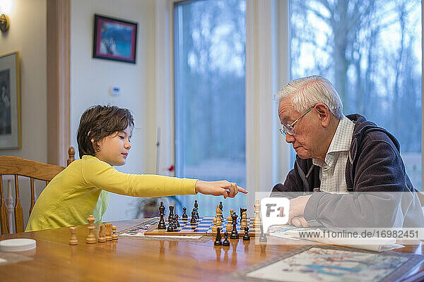 Ein Junge macht einen Schachzug  während sein Großvater zusieht