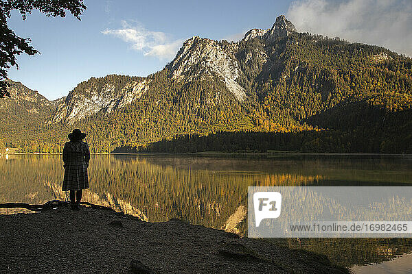 A woman stands in the shadows of a mountain by the lake in Germany