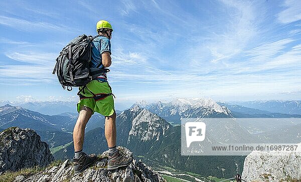Bergsteiger auf einem Grat an einem gesicherten Klettersteig  blickt in die Ferne  Mittenwalder Höhenweg  Karwendelgebirge  Mittenwald  Bayern  Deutschland  Europa