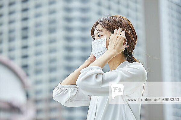 Junge japanische Geschäftsfrau mit Maske in der heißen Sommerzeit in der Innenstadt von Tokio