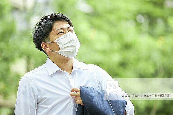 Junger japanischer Geschäftsmann mit Maske im heißen Sommer in der Innenstadt von Tokio