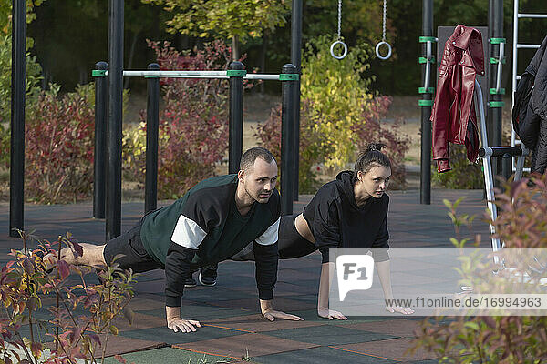 Athletisches junges Paar macht Plank-Übungen im Park Spielplatz