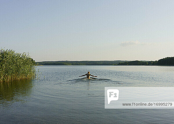 Boy swimming in sunny tranquil lake  Uckermark  Germany