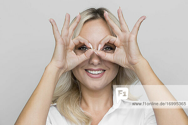 Porträt verspielte Frau gestikulierend Fingerbrille