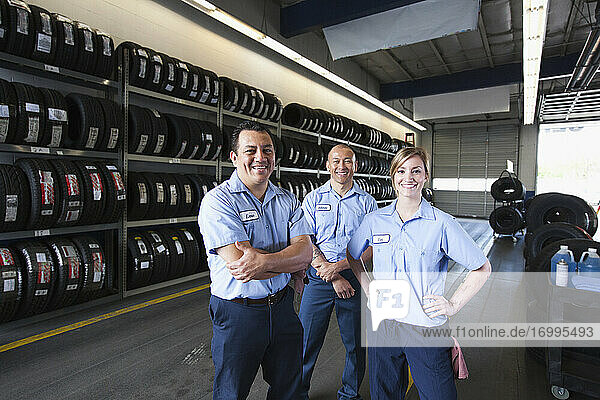 Portrait of smiling mechanics in auto repair shop  two men and a woman