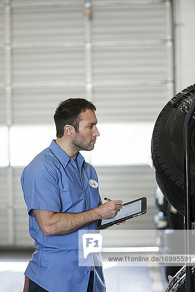 Männlicher Mechaniker bei der Inventarisierung neuer Reifen in einer Autowerkstatt