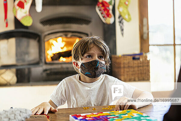 Junge mit Maske spielt Brettspiel zu Hause