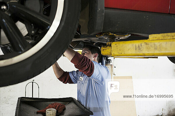 Mechaniker in einer Werkstatt arbeitet an der Unterseite eines Autos auf einer Hebebühne