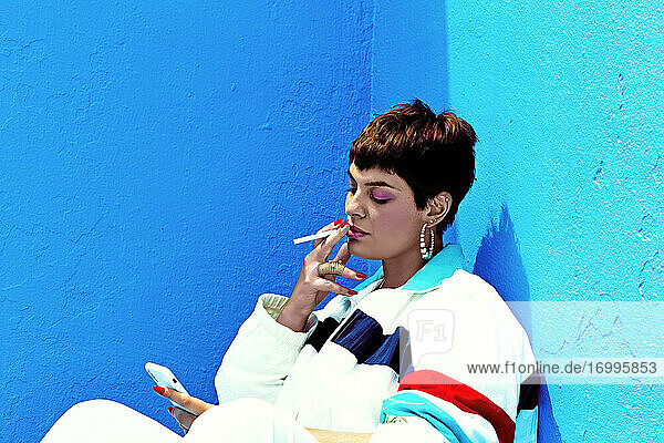 Woman wearing swag style smoking and checking her smartphone
