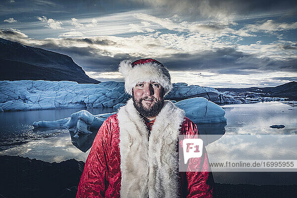 Island  Porträt eines lächelnden  als Weihnachtsmann verkleideten Mannes auf einem Gletscher