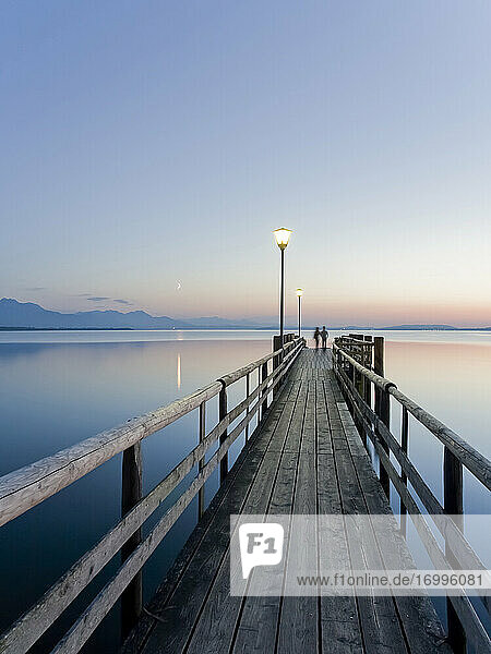 Germany  Bavaria  Clear sky over wooden pier on shore of Chiemsee lake at dusk