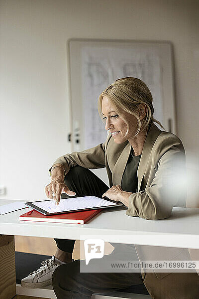 Geschäftsfrau  die zu Hause sitzend an einem digitalen Tablet arbeitet