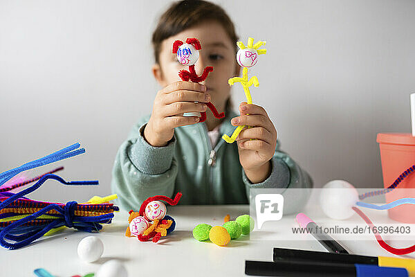 Mädchen spielt zu Hause mit kreativem Spielzeug aus Pfeifenreinigern und Pom-Pom